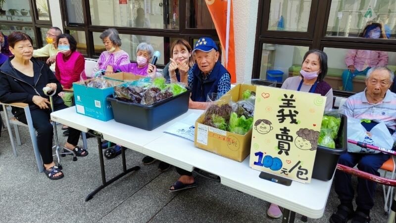 長輩自種採收好的水耕蔬菜會在校園進行義賣，感受到社會參與的成就感和貢獻度。(圖片來源/謙和賀日照中心)