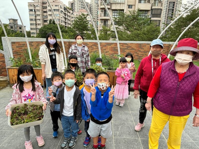 長輩與國小學生一起在日照的室外空間進行園藝活動。(圖片來源/愛迪樂)