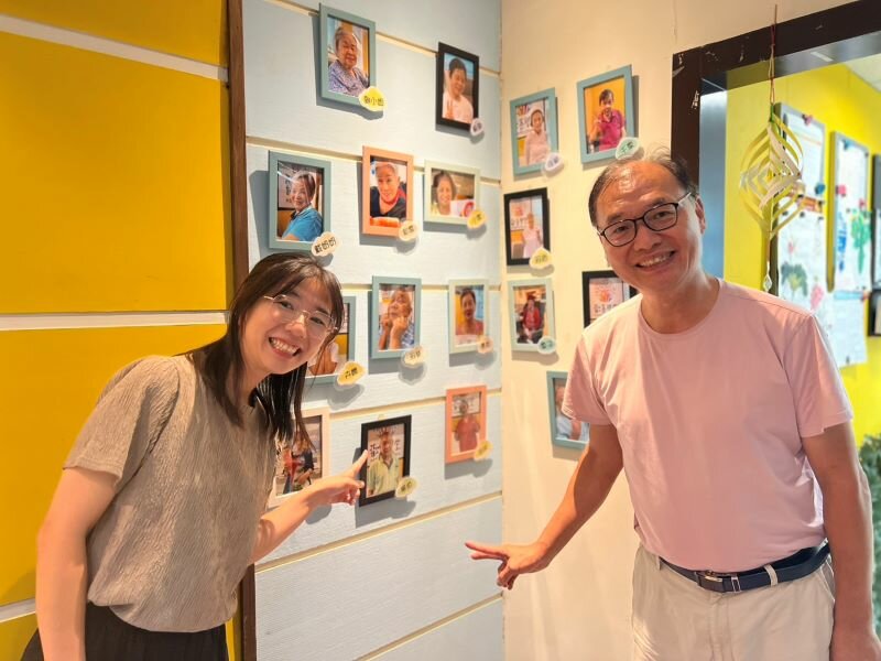 歡喜學堂入口貼滿長輩的「歡喜臉譜」，圖為前理事長吳忠泰（右）、秘書長楊雅評（左）。(攝影/侯俐安)