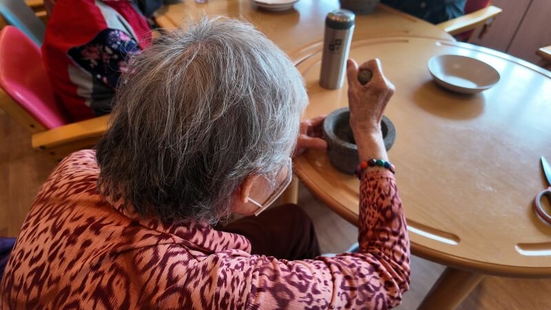 阿嬤手裡握著擂茶棒，專注地在缽中研磨。(圖片來源/侯勝宗)