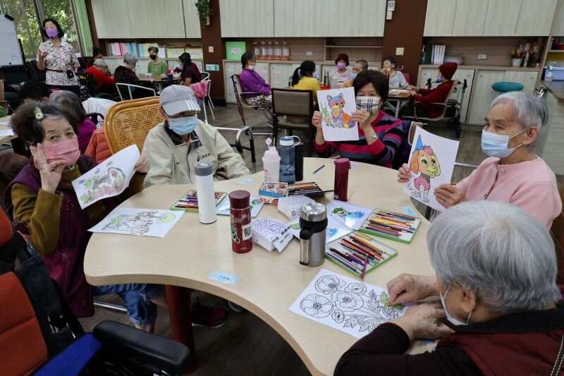 日照中心一早的繪畫課程，長輩得意地秀出作品。（攝影/侯俐安）