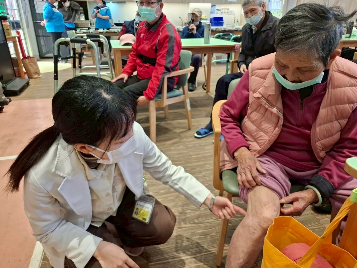 秀傳醫院的中醫師（左）定期到各個日照中心照顧長輩的健康，包括指導穴位按摩等。（圖片來源／秀傳長照體系）